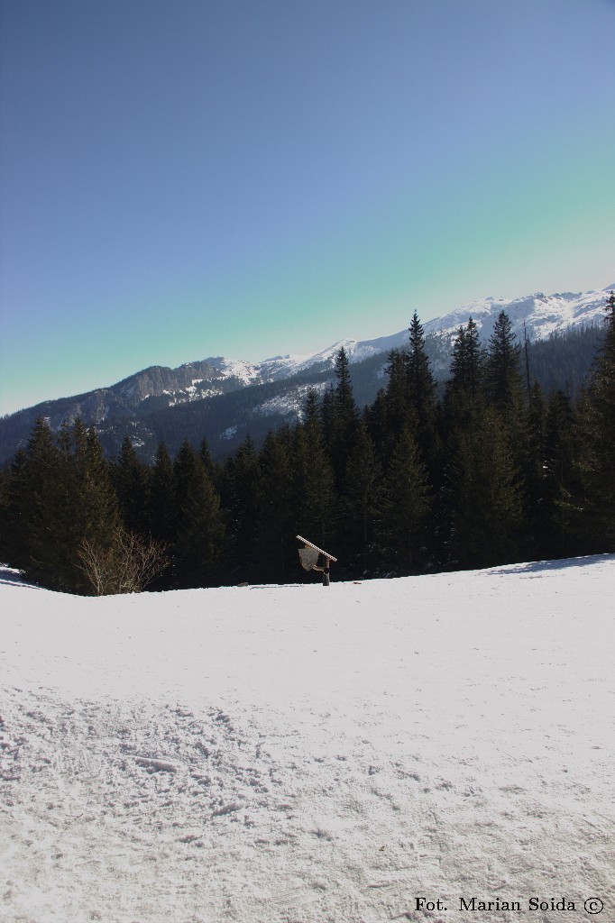 Ławka przed schroniskiem cała pod śniegiem, widok na Kasprowy Zawrat i Uhrocie